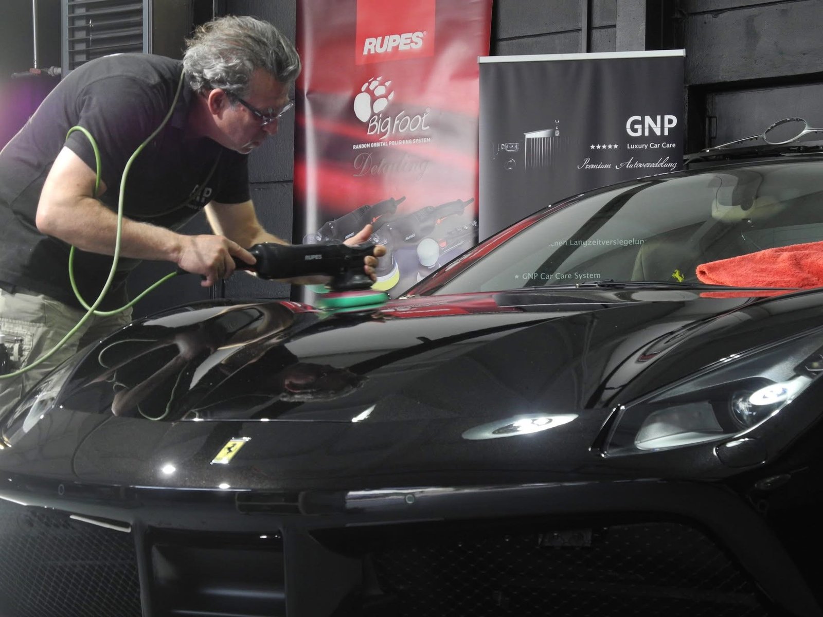 GNP Mitarbeiter poliert einen dunklen Ferrari mit der Maschine